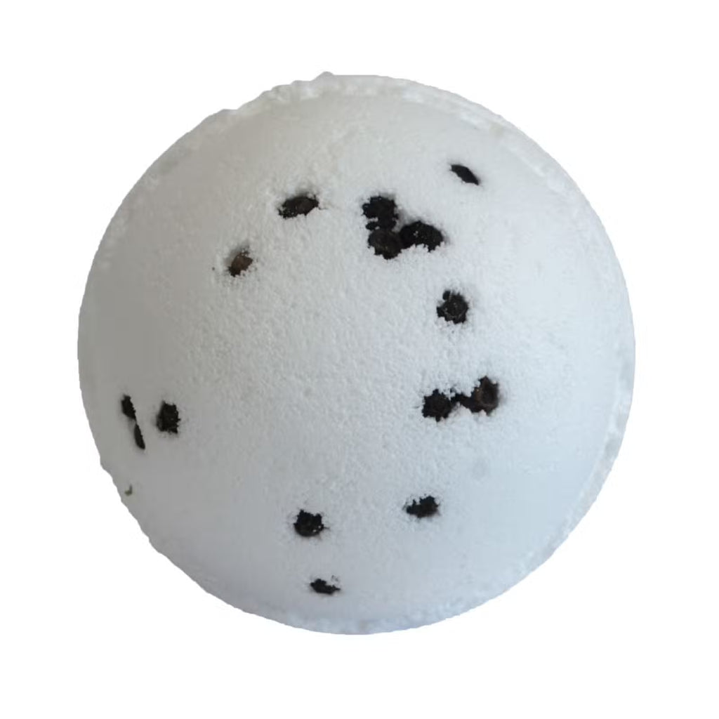 White gin and tonic bath bomb with black peppercorn specks on white background