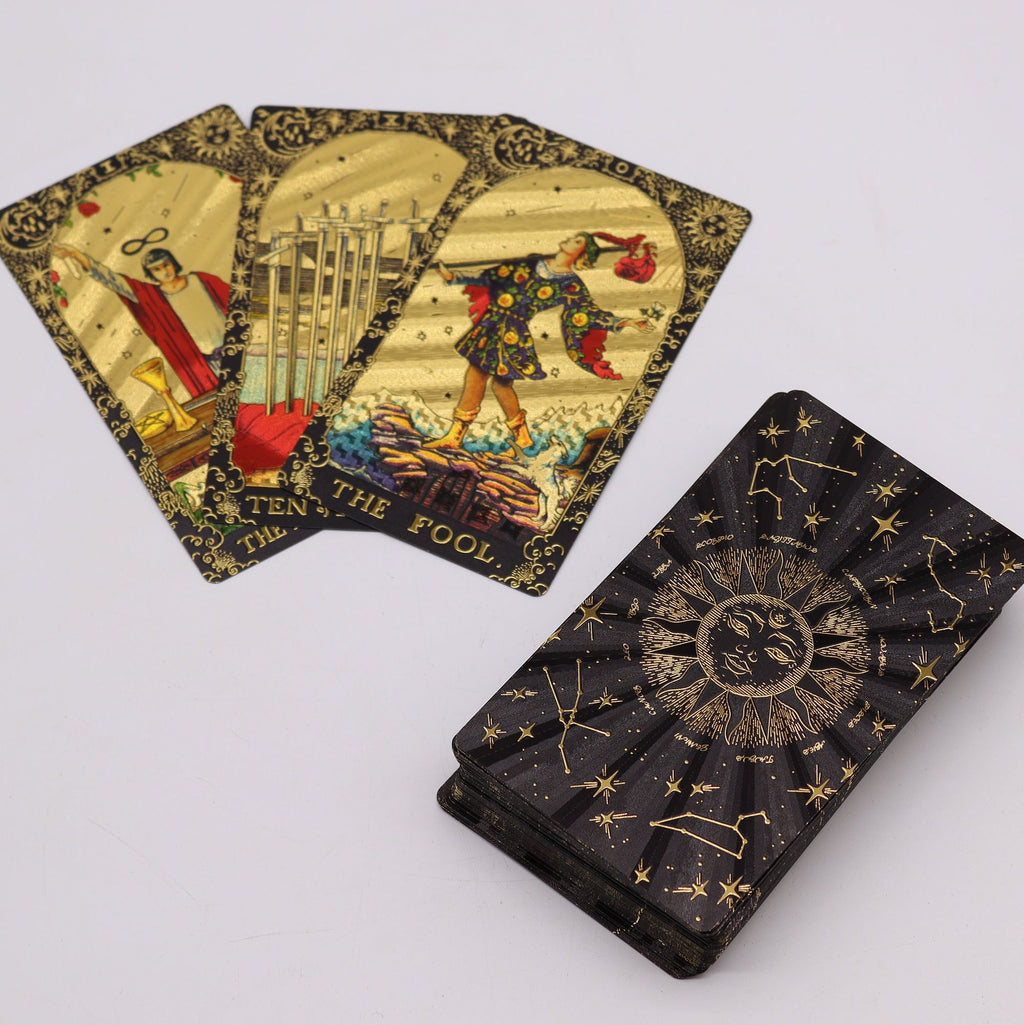 Gold foil tarot cards fanned out showing The Fool card with black celestial constellation card backs UK