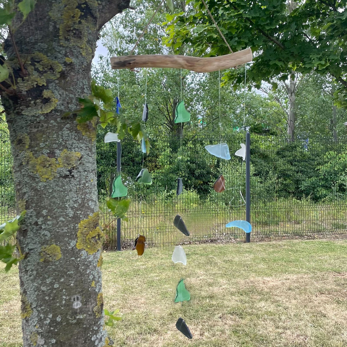 Five string coloured glass wind chime — vibrant pieces shimmer in sunlight