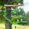 Green glass heart wind chime — hanging outdoors in garden setting