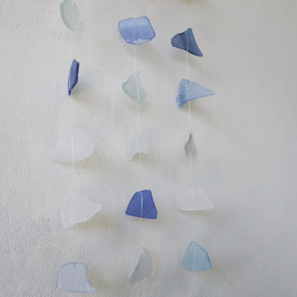 Three drop glass wind chime in blue and white displayed outdoors